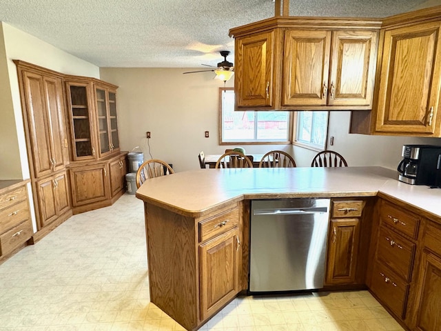 kitchen with light floors, a peninsula, dishwasher, and brown cabinets