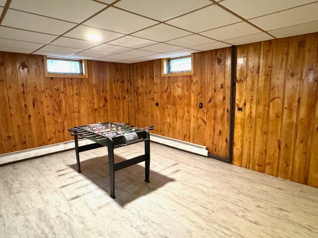 recreation room featuring a baseboard radiator, wood finished floors, wooden walls, and a paneled ceiling