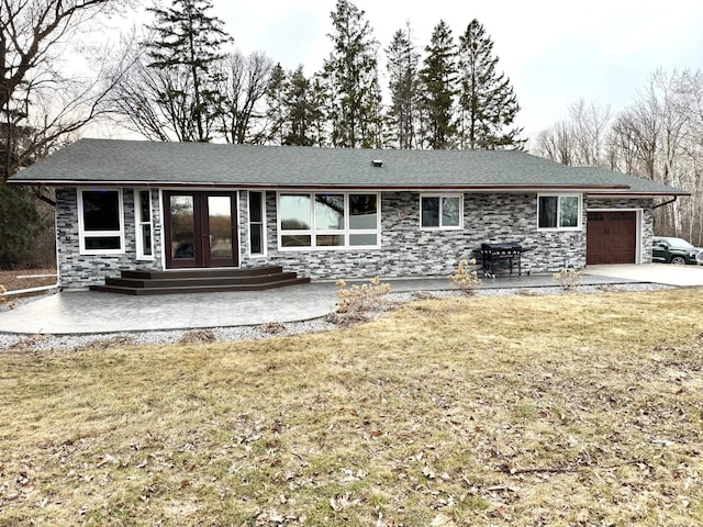 rear view of property featuring a lawn, french doors, entry steps, and a garage