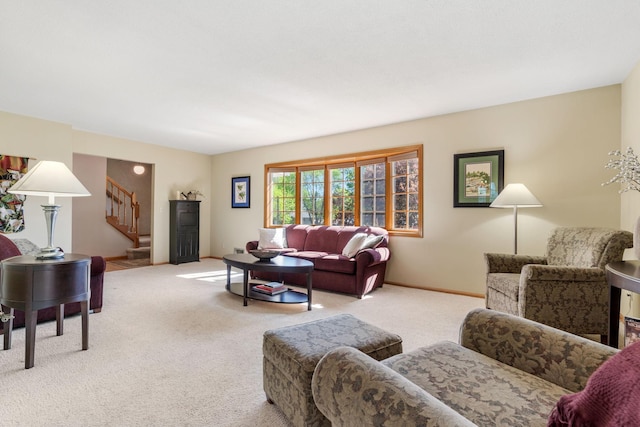 carpeted living area featuring stairway and baseboards