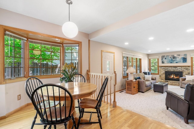 dining room with baseboards, light wood-type flooring, a fireplace, and recessed lighting