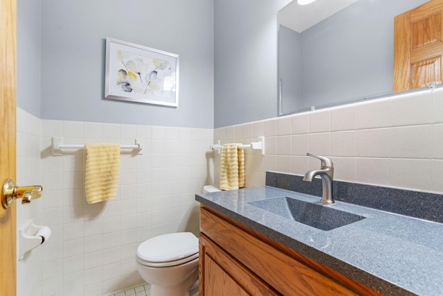 bathroom featuring tile walls, toilet, vanity, and wainscoting