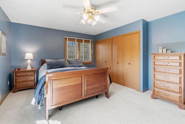 bedroom featuring light colored carpet, two closets, ceiling fan, and baseboards