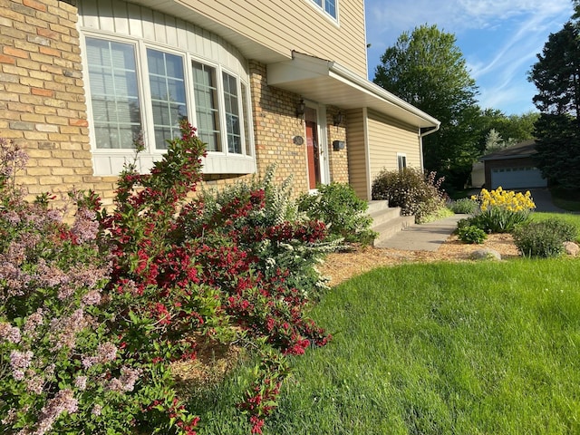 view of exterior entry featuring brick siding and a lawn