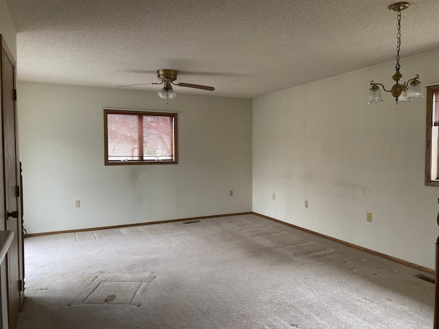 2509 6th St SW, Willmar, MN 56201 - carpeted spare room featuring ceiling fan with notable chandelier, baseboards, visible vents, and a textured ceiling