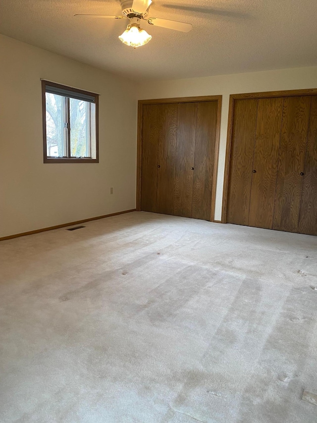 2509 6th St SW, Willmar, MN 56201 - unfurnished bedroom with multiple closets, visible vents, carpet, and a ceiling fan