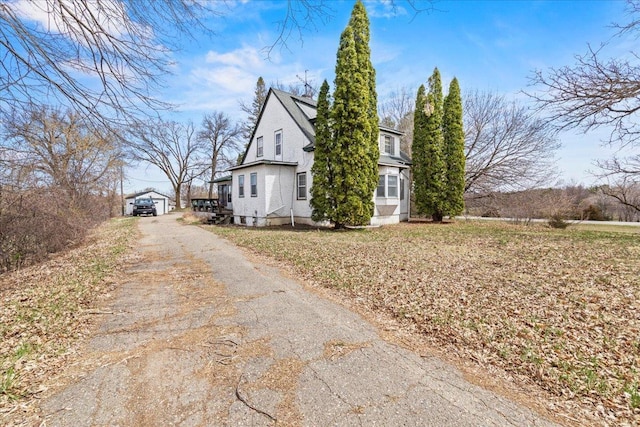 view of side of home with an outdoor structure and driveway