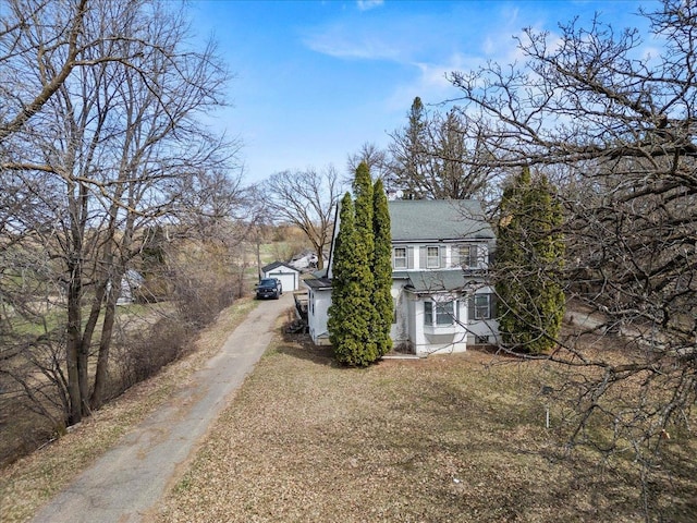 view of home's exterior with central AC, driveway, a shingled roof, and an outbuilding
