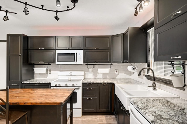 kitchen featuring a sink, white appliances, wooden counters, light wood-style flooring, and decorative backsplash
