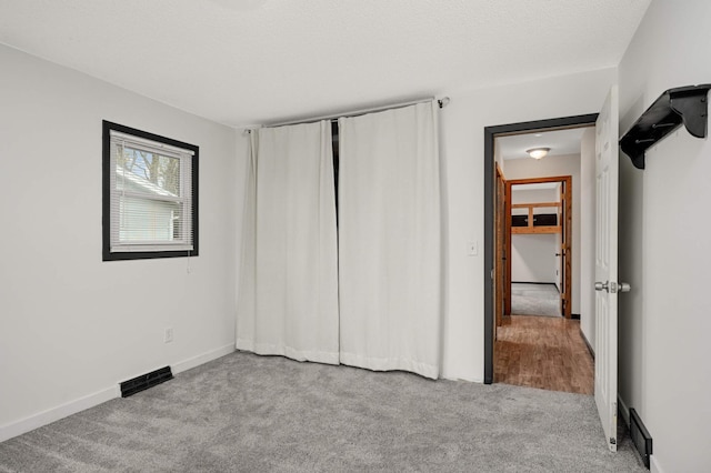 unfurnished bedroom featuring visible vents, carpet flooring, baseboards, and a closet