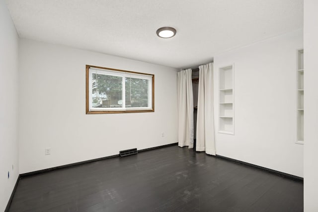 unfurnished bedroom with dark wood-type flooring, baseboards, and visible vents