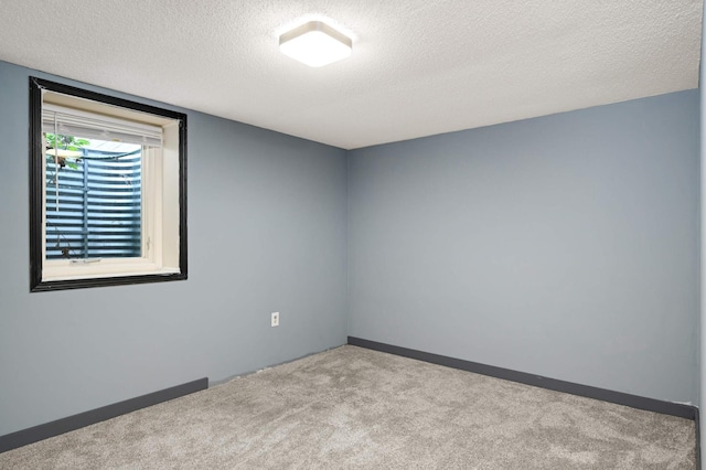 carpeted empty room featuring a textured ceiling and baseboards
