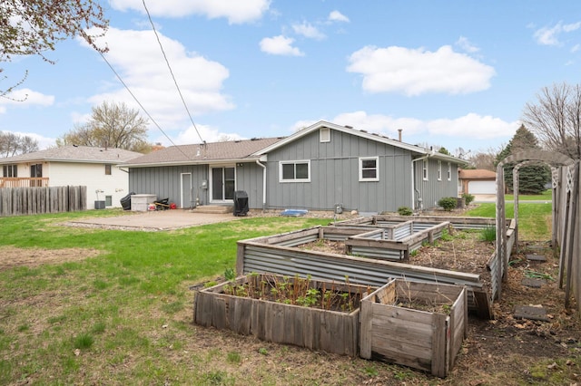 rear view of house with fence, board and batten siding, a vegetable garden, a patio area, and a yard