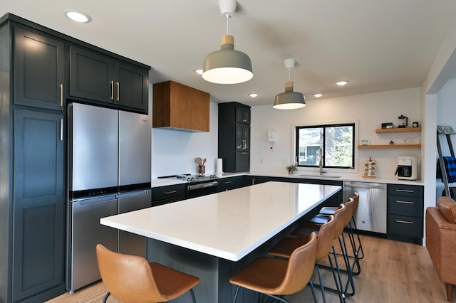 1011 Burgs Park Dr, Shell Lake, WI 54871 - kitchen with stainless steel appliances, light wood-style flooring, a sink, decorative light fixtures, and a breakfast bar area