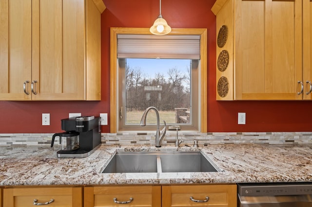 kitchen featuring a sink, light brown cabinetry, light stone counters, pendant lighting, and stainless steel dishwasher