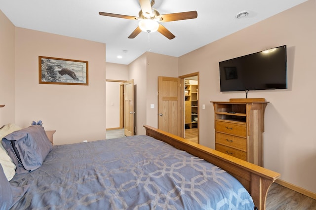 bedroom featuring baseboards, visible vents, wood finished floors, and a ceiling fan