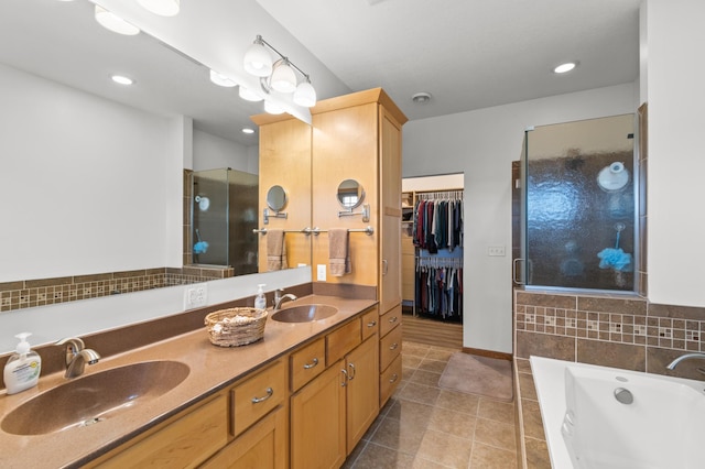 bathroom with tile patterned floors, a stall shower, a garden tub, and a sink