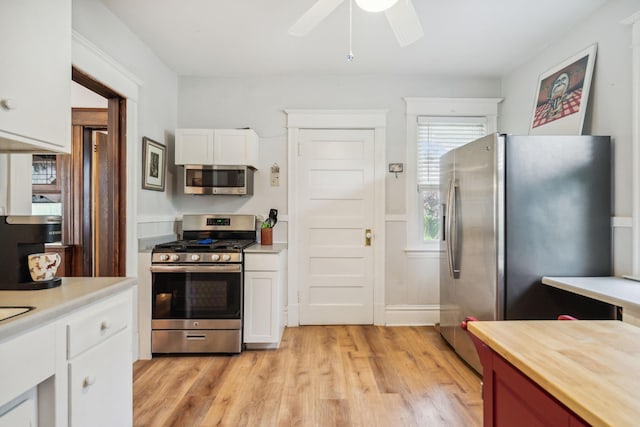 3304 Longfellow Ave, Minneapolis, MN 55407 - kitchen featuring white cabinets, light wood-style floors, wooden counters, stainless steel appliances, and a ceiling fan