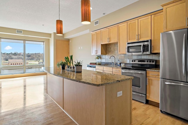240 Spring St Unit 413, Saint Paul, MN 55102 - kitchen featuring appliances with stainless steel finishes, a sink, a center island, decorative backsplash, and dark stone counters