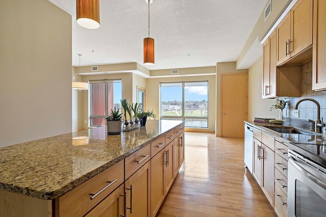 240 Spring St Unit 413, Saint Paul, MN 55102 - kitchen featuring a sink, light wood-style floors, a textured ceiling, a center island, and decorative light fixtures