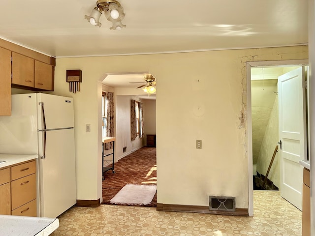 kitchen with freestanding refrigerator, arched walkways, light countertops, a ceiling fan, and crown molding