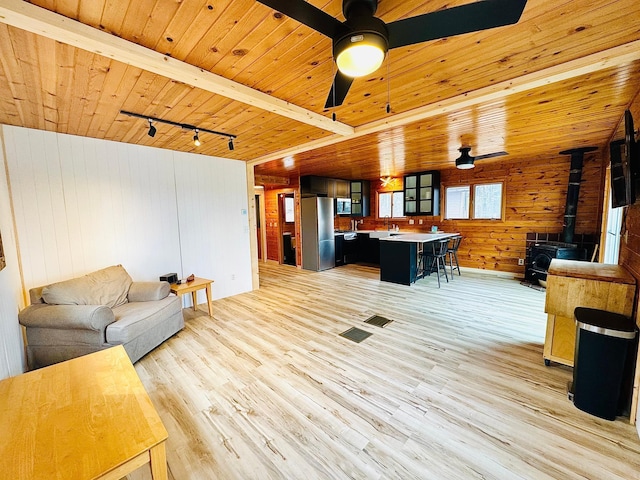 41820 Bald Eagle Dr, Marcell Twp, MN 56628 - living area with wood ceiling, a wood stove, wood walls, light wood finished floors, and ceiling fan