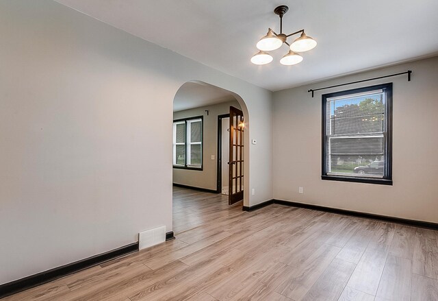 423 1st St NW, Faribault, MN 55021 - empty room with arched walkways, a chandelier, light wood-style flooring, and baseboards