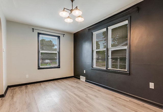423 1st St NW, Faribault, MN 55021 - spare room featuring a chandelier, light wood finished floors, and baseboards