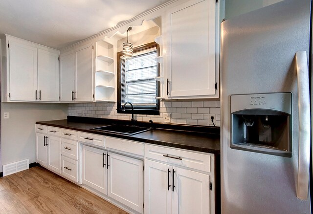 423 1st St NW, Faribault, MN 55021 - kitchen featuring fridge with ice dispenser, a sink, dark countertops, and white cabinetry