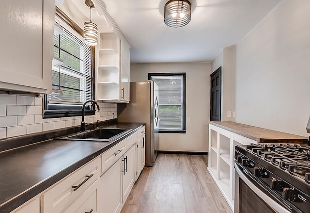 423 1st St NW, Faribault, MN 55021 - kitchen featuring open shelves, stainless steel range with gas stovetop, a sink, dark countertops, and light wood-style floors