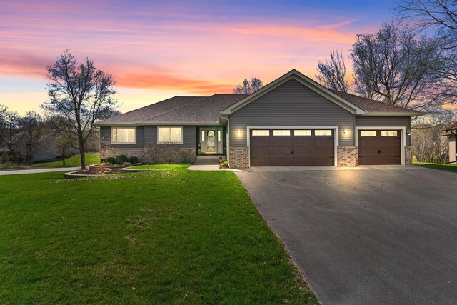 single story home with asphalt driveway, an attached garage, a lawn, brick siding, and roof with shingles