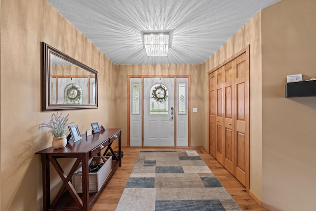 foyer entrance with a chandelier and light wood-style floors