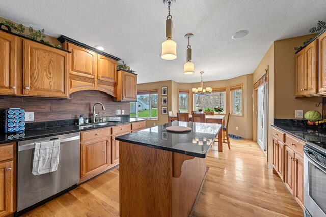 kitchen featuring appliances with stainless steel finishes, a sink, a chandelier, a center island, and tasteful backsplash