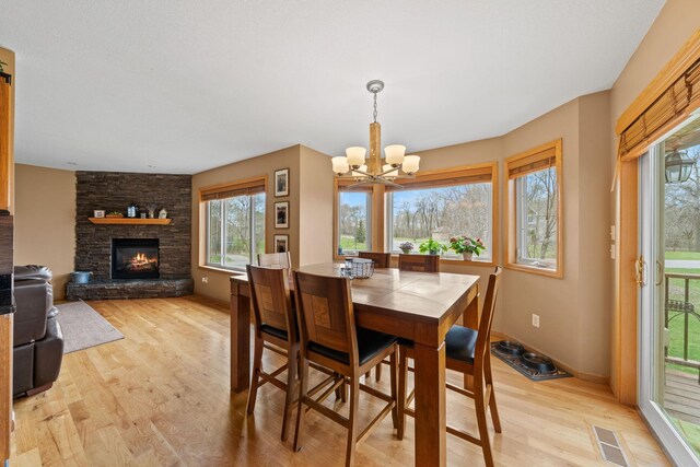 dining space with a chandelier, light wood-type flooring, a fireplace, and baseboards