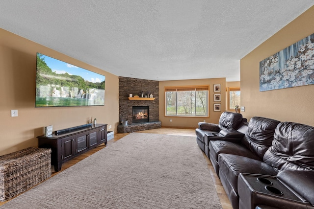 living room with light wood-style floors, a textured ceiling, and a stone fireplace