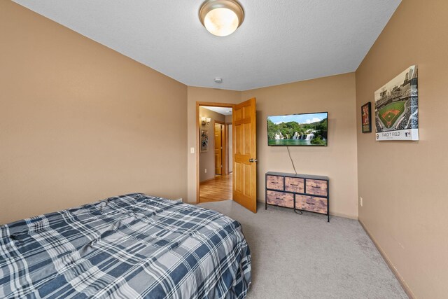 bedroom featuring light colored carpet and a textured ceiling