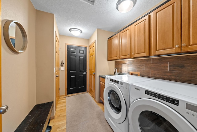 laundry room with washer and dryer, cabinet space, light wood-style flooring, and a textured ceiling