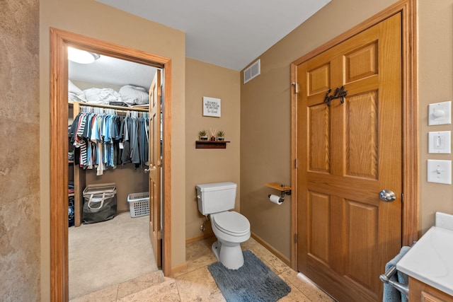 bathroom featuring toilet, tile patterned flooring, and a walk in closet
