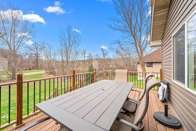 wooden deck featuring outdoor dining space and a lawn