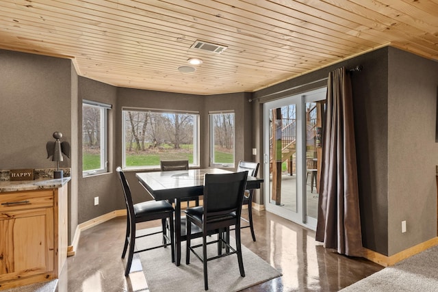 dining room with wood ceiling, baseboards, concrete floors, and a textured wall