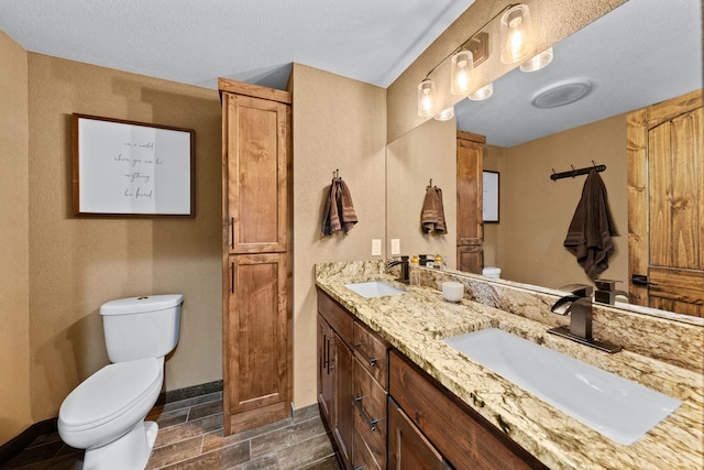 full bathroom with toilet, baseboards, and double vanity