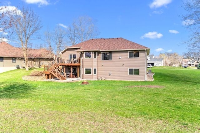 back of property with stairway, a deck, a lawn, and a shingled roof