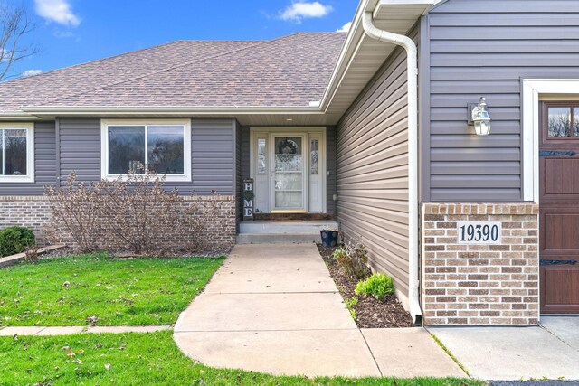 19390 Queen Cir NW, Elk River, MN 55330 - entrance to property featuring roof with shingles, brick siding, and a yard