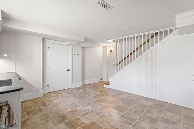 9730 177th Ave SE, Fairmount, ND 58030 - finished below grade area with baseboards, visible vents, stone finish floor, and stairway