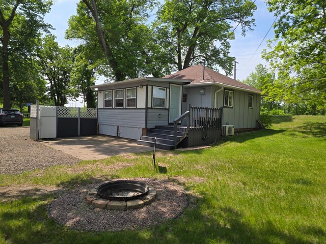 50967 Wymer Lake Trl, Hobart Twp, MN 56544 - view of front of house featuring an outdoor fire pit, a front lawn, board and batten siding, a cooling unit, and a shingled roof