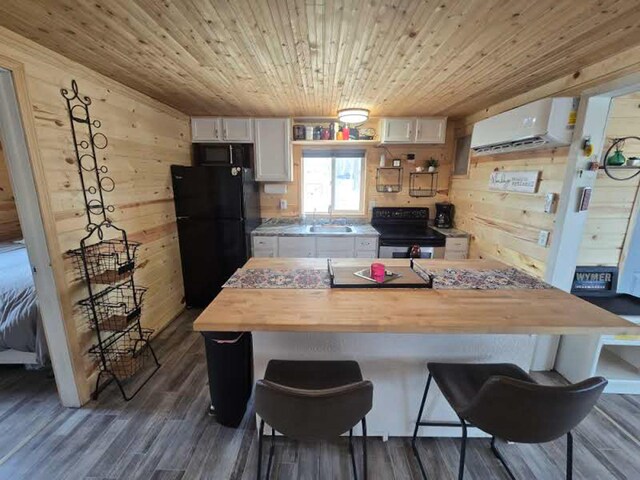 50967 Wymer Lake Trl, Hobart Twp, MN 56544 - kitchen with black appliances, a sink, butcher block counters, white cabinets, and a wall mounted air conditioner