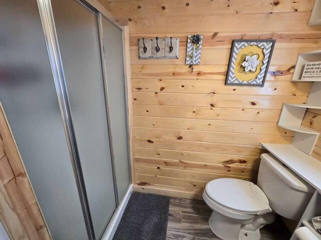 50967 Wymer Lake Trl, Hobart Twp, MN 56544 - bathroom featuring a stall shower, toilet, wood walls, and wood finished floors