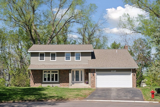 view of front of house featuring brick siding, driveway, an attached garage, a chimney, and a front yard