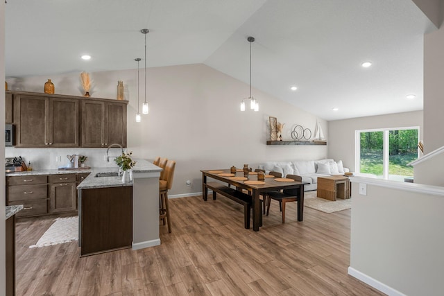 5928 Th St W, Lakeville, MN 55044 - kitchen with a sink, dark brown cabinetry, lofted ceiling, stainless steel microwave, and light wood finished floors