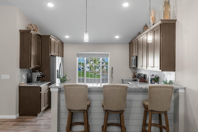 5928 Th St W, Lakeville, MN 55044 - kitchen with stainless steel appliances, tasteful backsplash, light wood-type flooring, a peninsula, and a breakfast bar